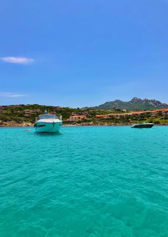 Motor yachts anchored over clear turquoise water off the Sardinian coast